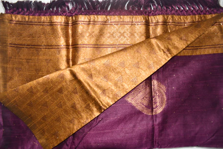 Close-up of elegant women's clothing fabrics in rich purple and gold tones displayed online.