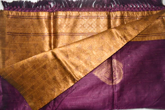 A close-up of a rich purple and gold fabric draped elegantly, symbolizing the royal theme of the Kingdom Party.