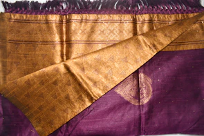 Close-up of luxurious fabric textures in rich purples and golds, showcasing intricate weaving details.