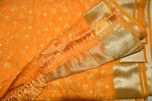 A crafted saree folded neatly, highlighting its delicate borders with gold threadwork.