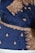 A rich blue fabric adorned with intricate gold embroidery, featuring floral and paisley patterns. The ornate designs are meticulously stitched with glittering gold thread, highlighting an elaborate and traditional textile craftsmanship.