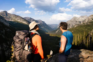 Hikers standing atop a mountain peak, overlooking a vast valley below.