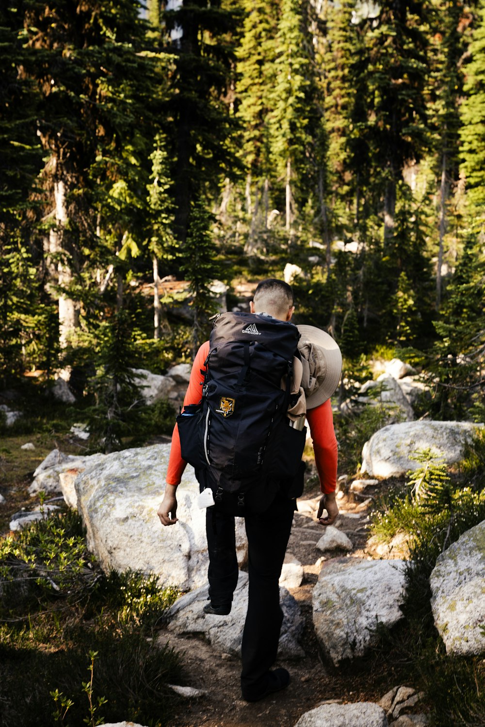 a man with a backpack walking up a trail in the woods