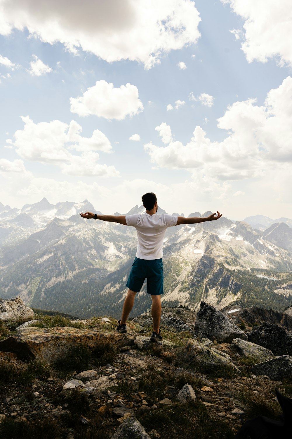 un homme debout au sommet d’une montagne, les bras tendus