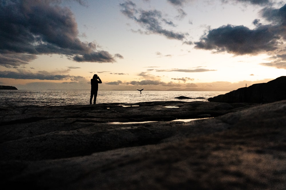 a man standing on top of a beach next to the ocean