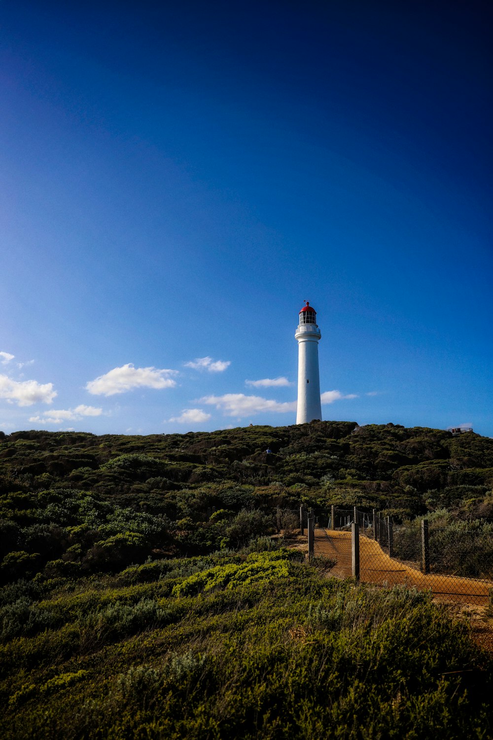 a lighthouse on a hill with a blue sky in the background