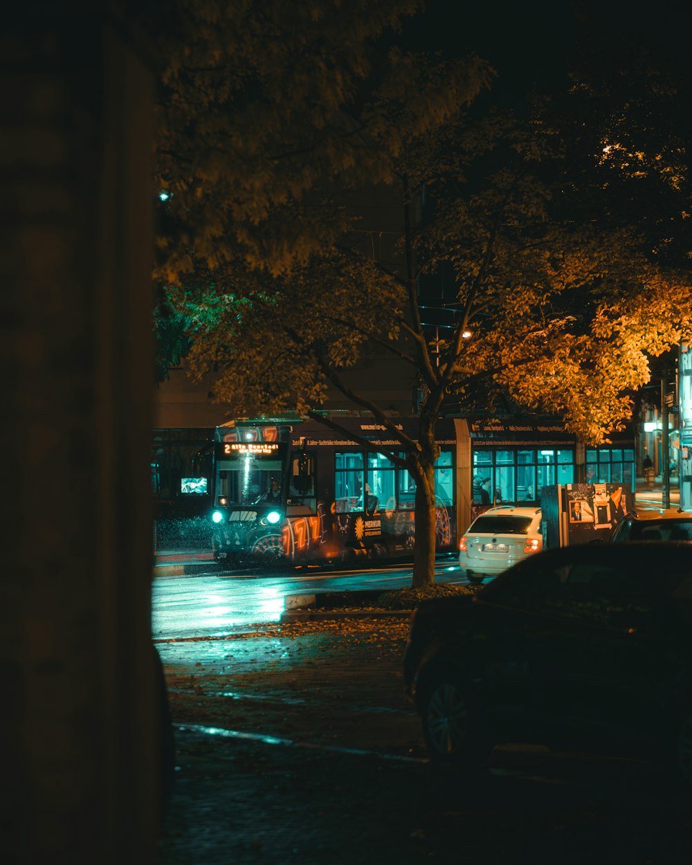 a city street at night with cars parked on the side of the road