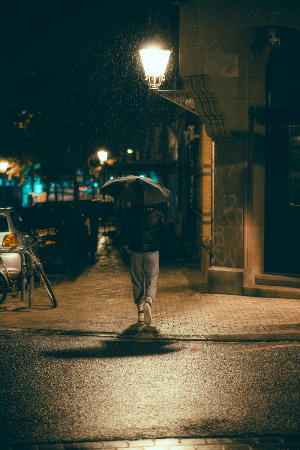 eine Person, die mit einem Regenschirm in der Hand eine Straße entlanggeht