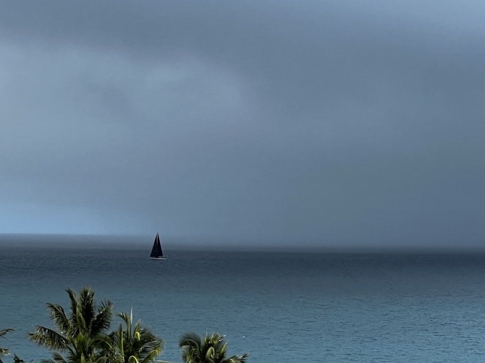 a sailboat in the ocean on a cloudy day