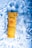 A yellow tube of sunscreen lotion labeled 'Lakmé Sun Expert' floats in clear blue water, surrounded by ripples and reflections.