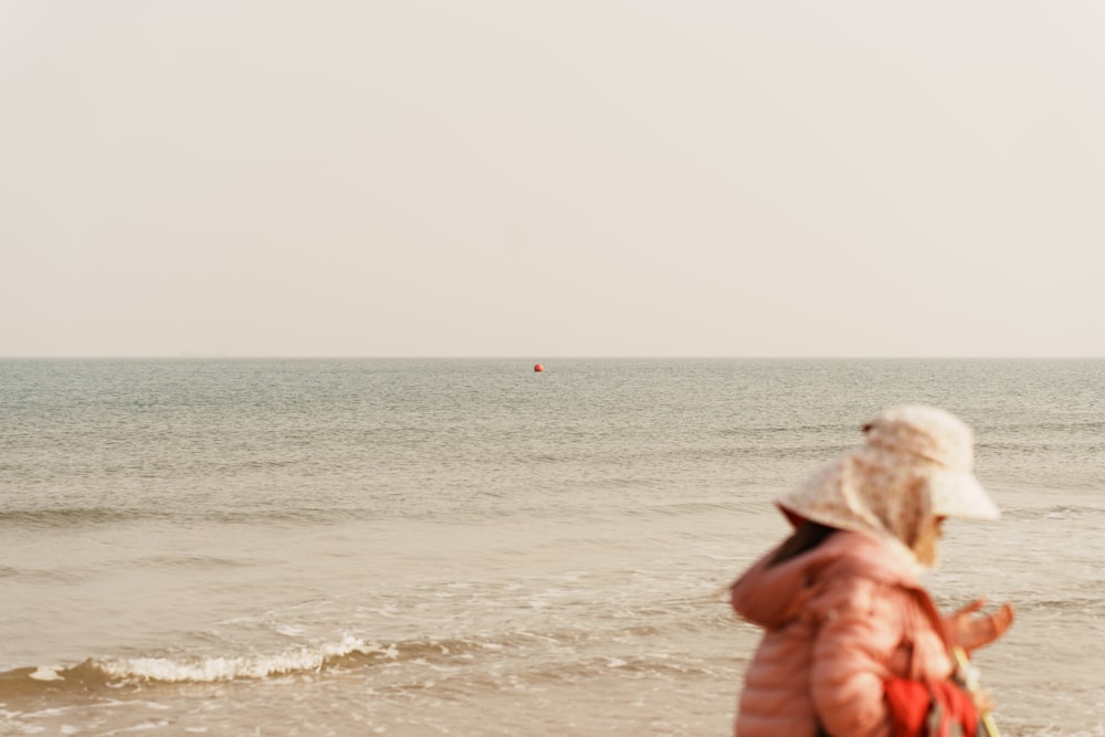 a woman standing on top of a beach next to the ocean