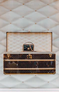 a louis vuitton trunk with a handbag on top of it