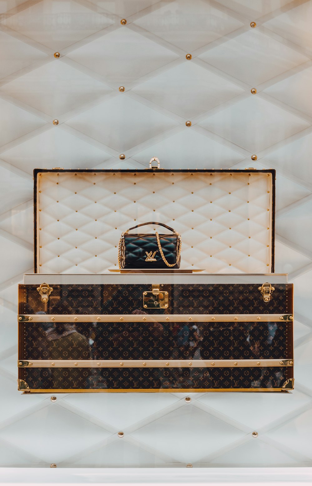 a louis vuitton trunk with a handbag on top of it