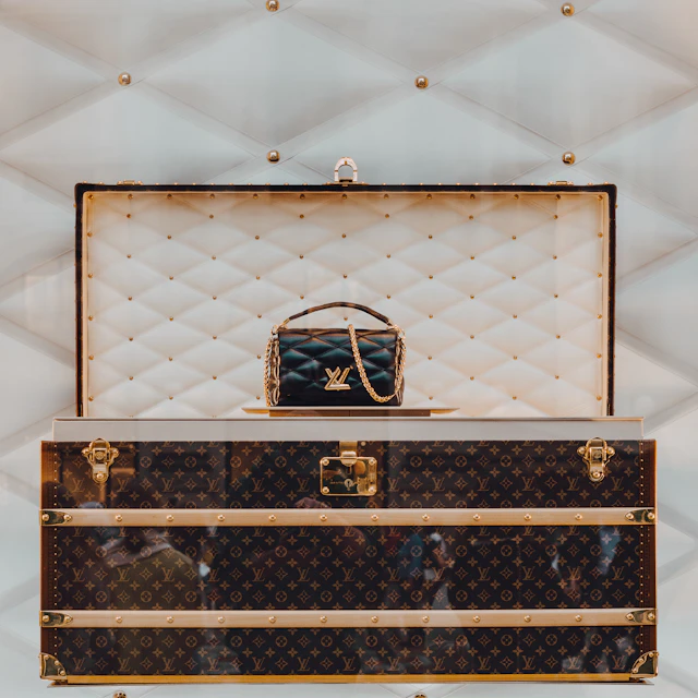 A Louis Vuitton trunk with a handbag resting on top of it