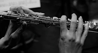 Close-up of a musician's hands expertly playing a silver flute in a high-end recording studio.