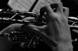 A close-up of hands playing a brass instrument passionately.