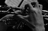 Black and white portrait of ritmovivo tuning his trumpet, focused and serene.