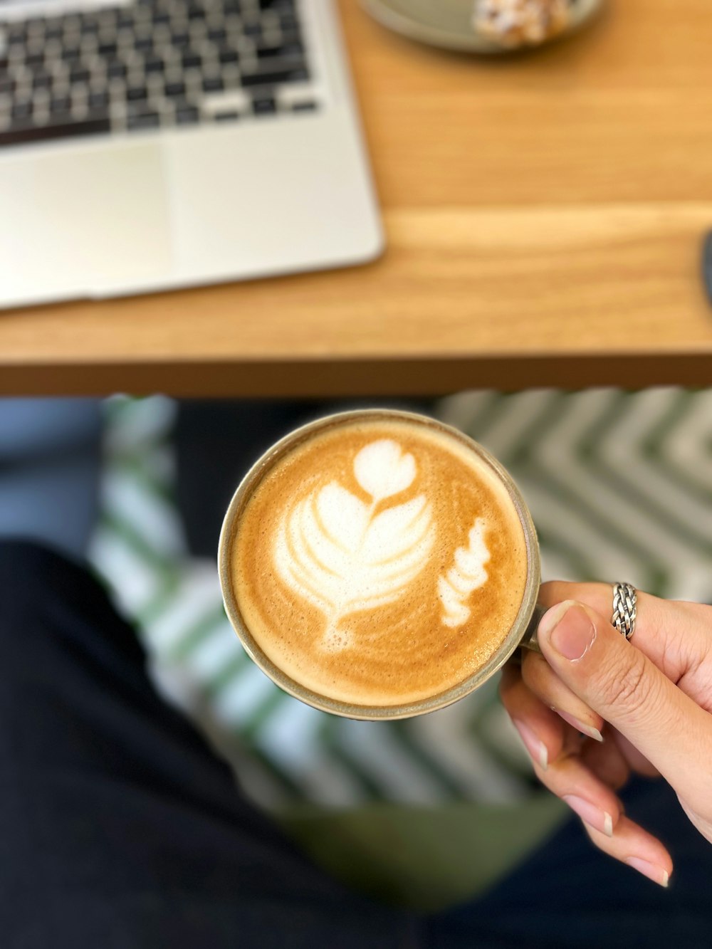 eine Person, die eine Tasse Kaffee vor einem Laptop hält