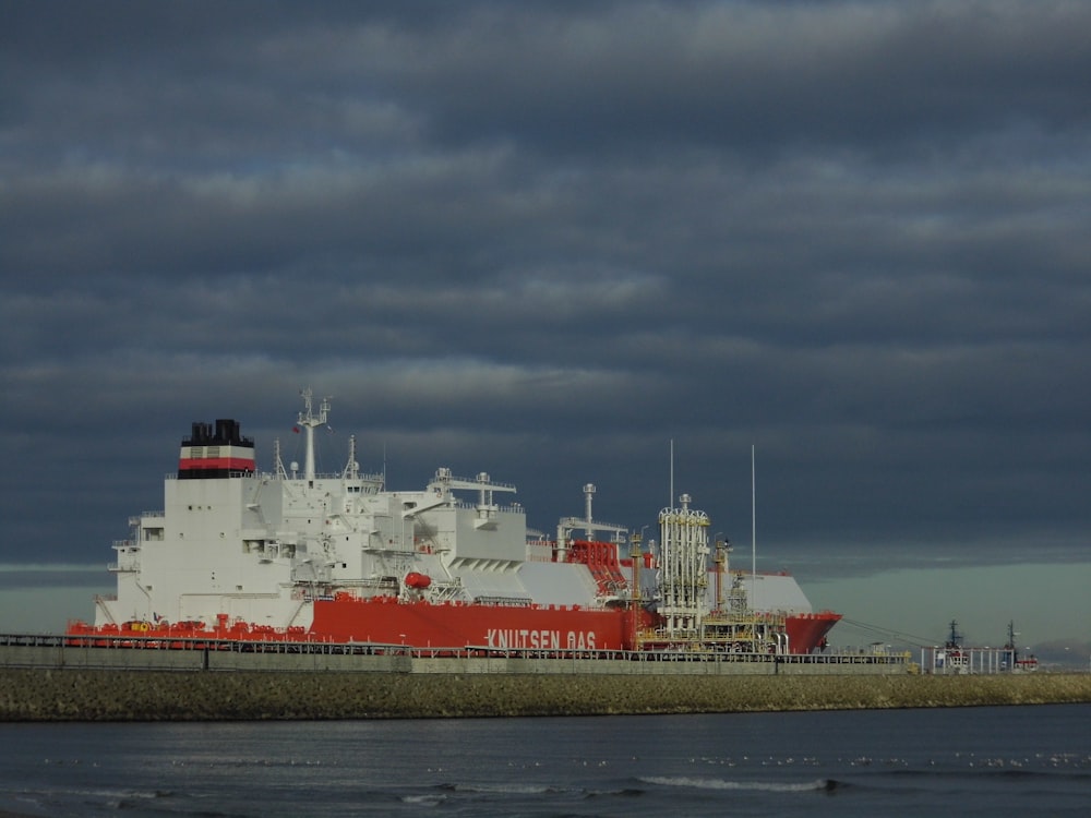 a large red and white ship in a body of water