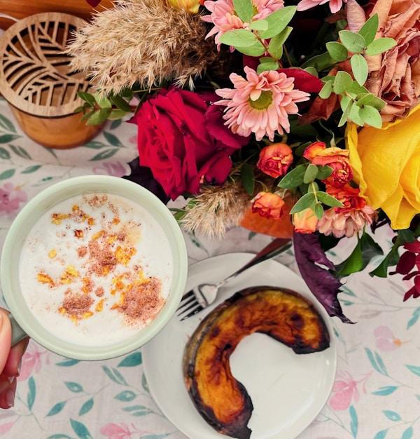 A bowl of oatmeal next to a plate of fruit and flowers