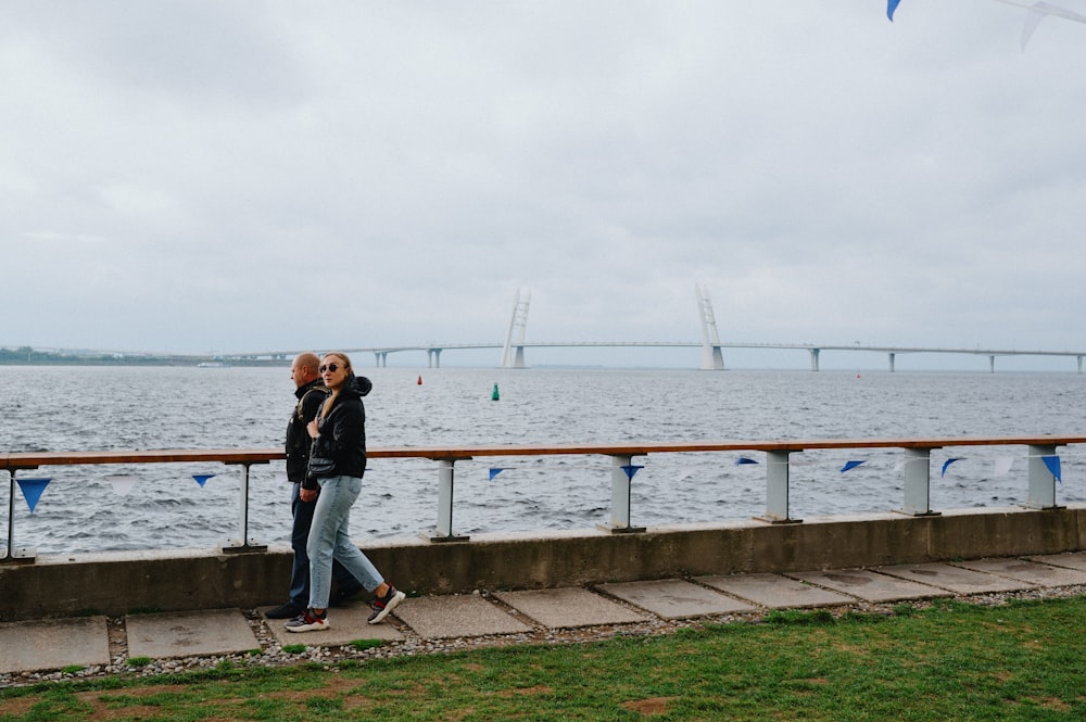 a man and a woman are standing on the side of the water