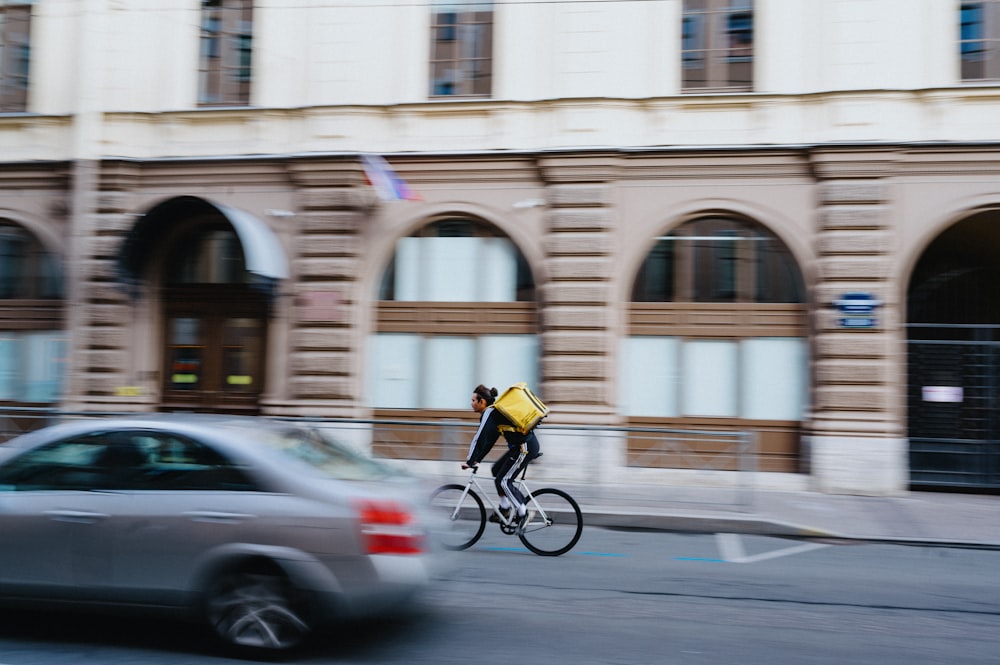 a man riding a bike down a street next to a car