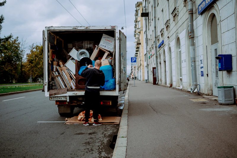 Hauler unloading furniture and boxes from the back of a box truck at the curb
