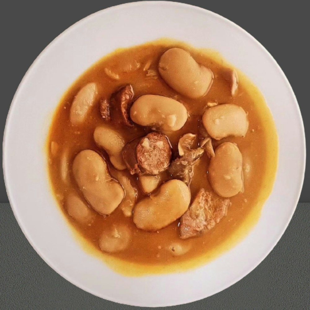 a white plate topped with a stew of beans and meat