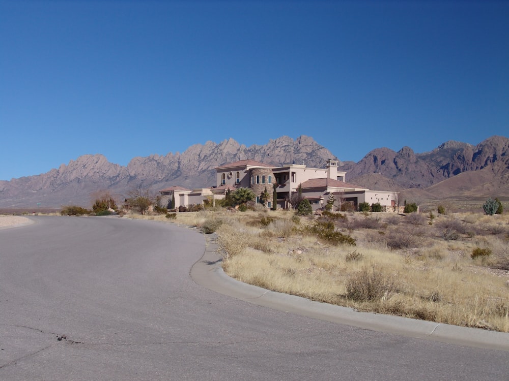 a house in the middle of a desert with mountains in the background