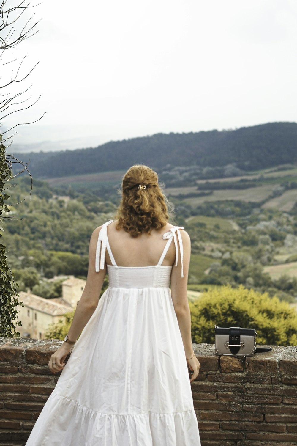 a woman in a white dress standing on a brick wall