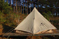 A family setting up a bright Campora tent on a sunny forest clearing.