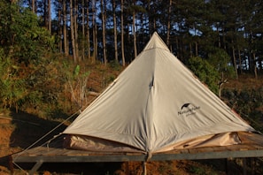 A cozy camping tent pitched in a lush forest clearing at sunset.
