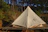 A tent set up in a forest clearing with solar panels charging gear nearby at sunset.