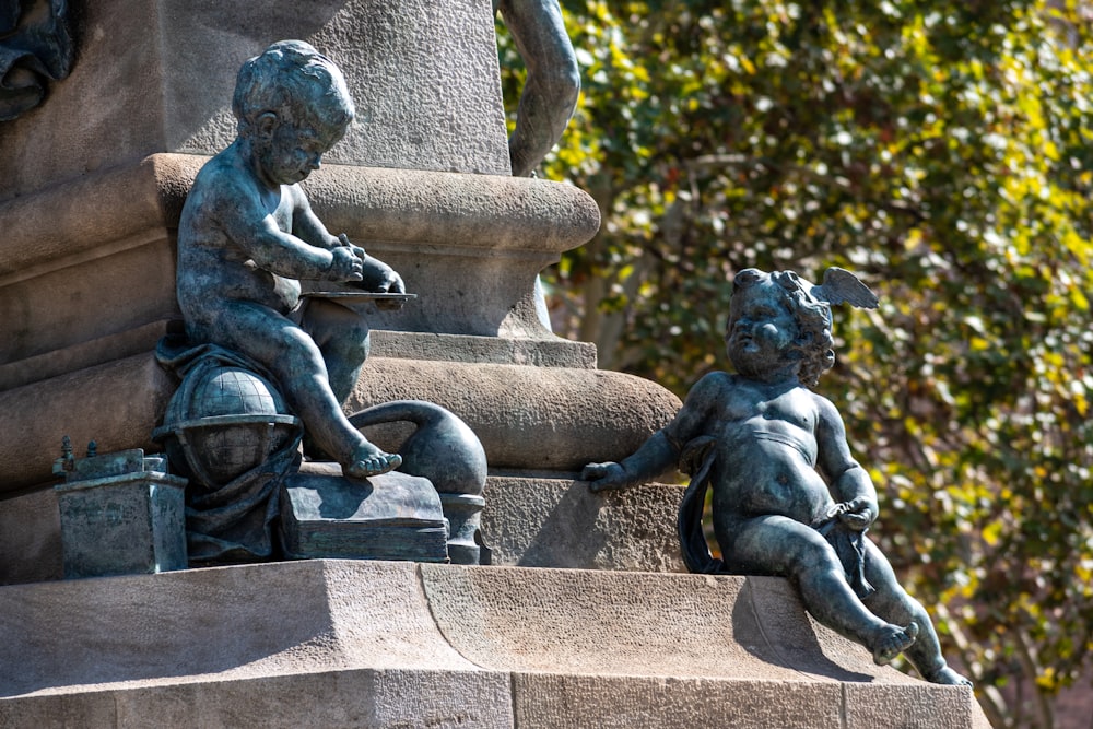 a statue of a boy and a girl sitting on a fountain