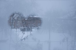 A snowy window scene with frosted glass and a small Christmas wreath hanging in the center.