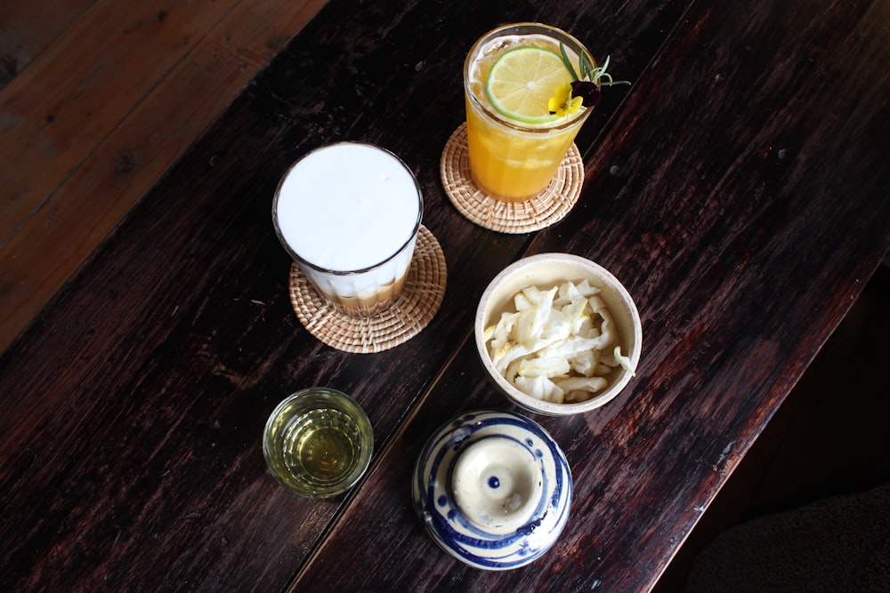 a wooden table topped with bowls of food and drinks
