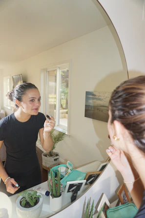 Soft natural light highlighting a customer applying lashes in front of a mirror.