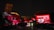 A nighttime scene featuring a historic building illuminated with red lights and projected images, including a large digital display celebrating the 100th anniversary of the republic on the right side. Turkish flags and decorations are visible, enhancing the festive atmosphere, with a clock tower in the background.