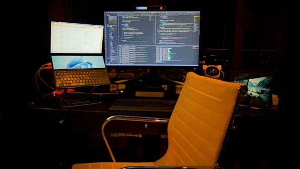 Developer coding custom software solutions on multiple monitors in a modern office.