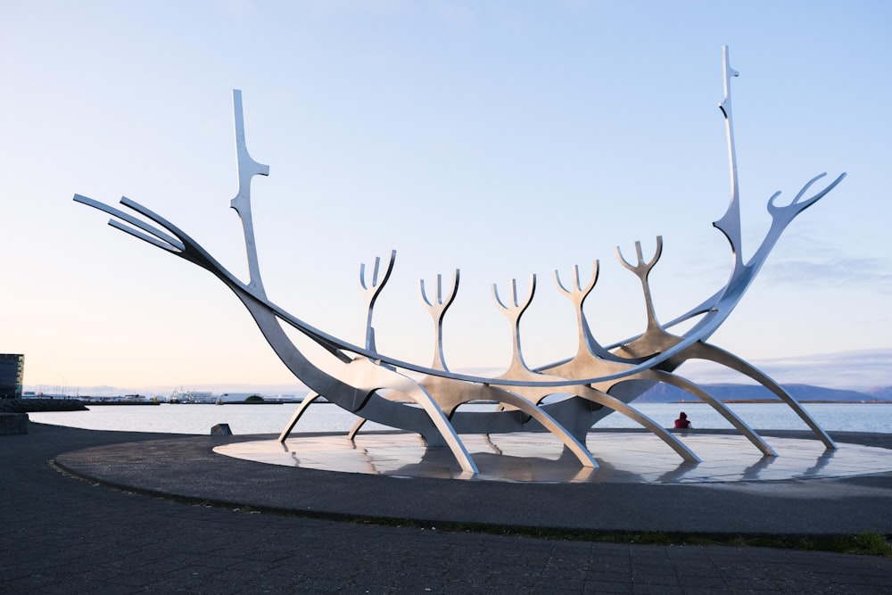 a large metal sculpture sitting in front of a body of water