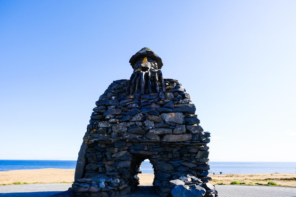 a stone sculpture of a face on a beach