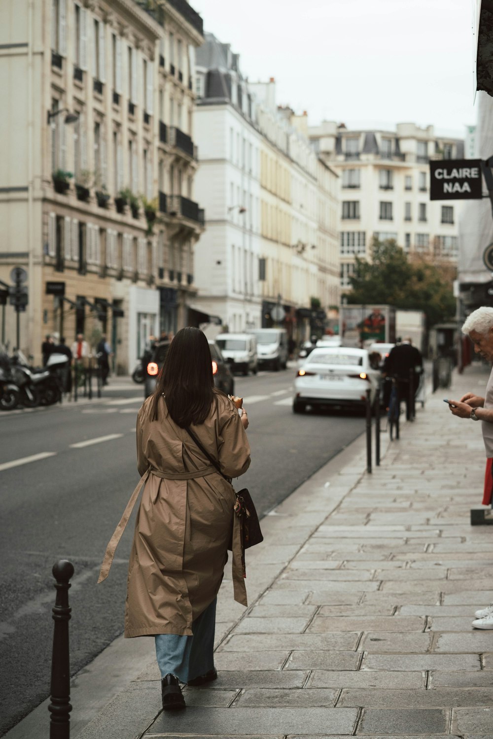 a woman walking down a street next to tall buildings