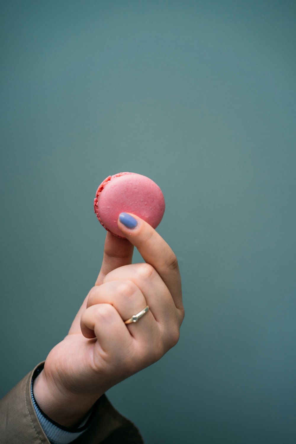 a person holding a pink doughnut in their hand