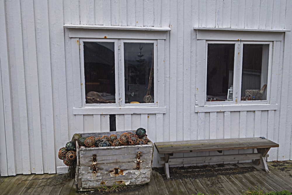 a bench sitting on a wooden deck next to a white building