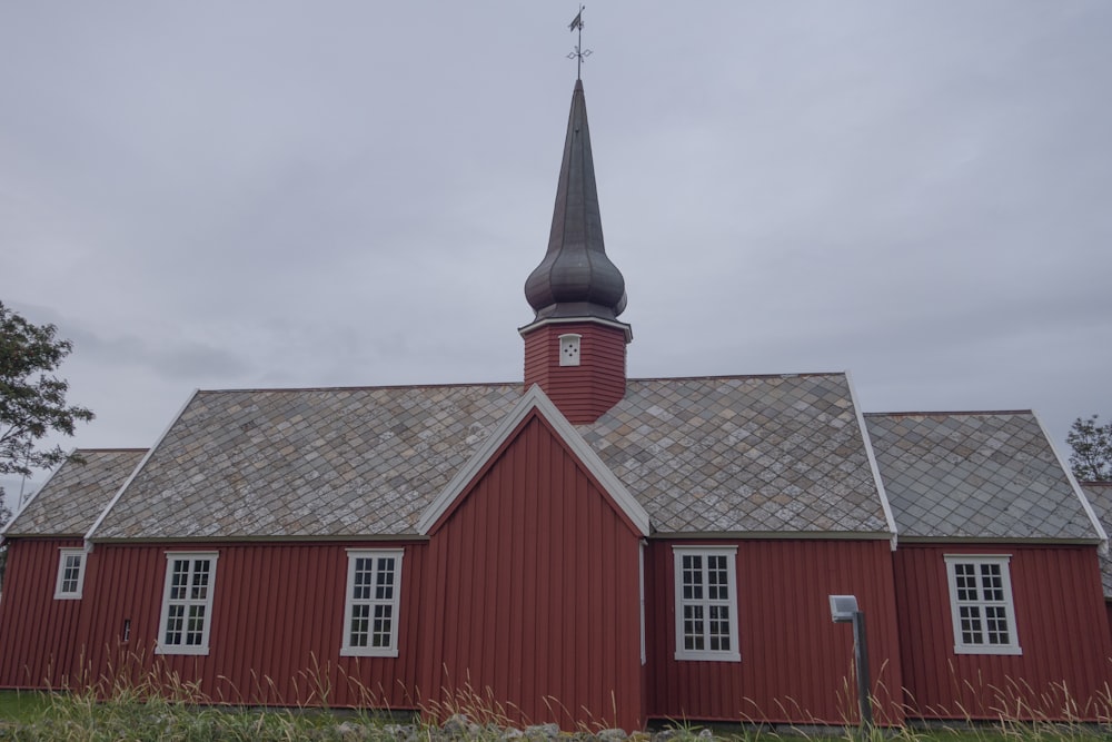 a red church with a steeple and a clock