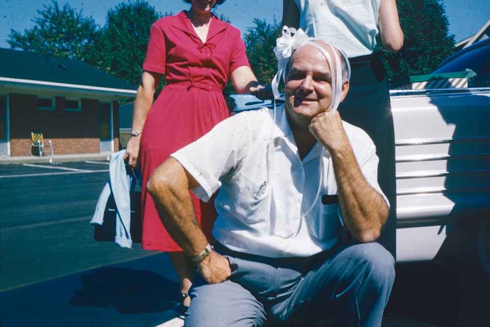 a man sitting on the back of a car next to a woman