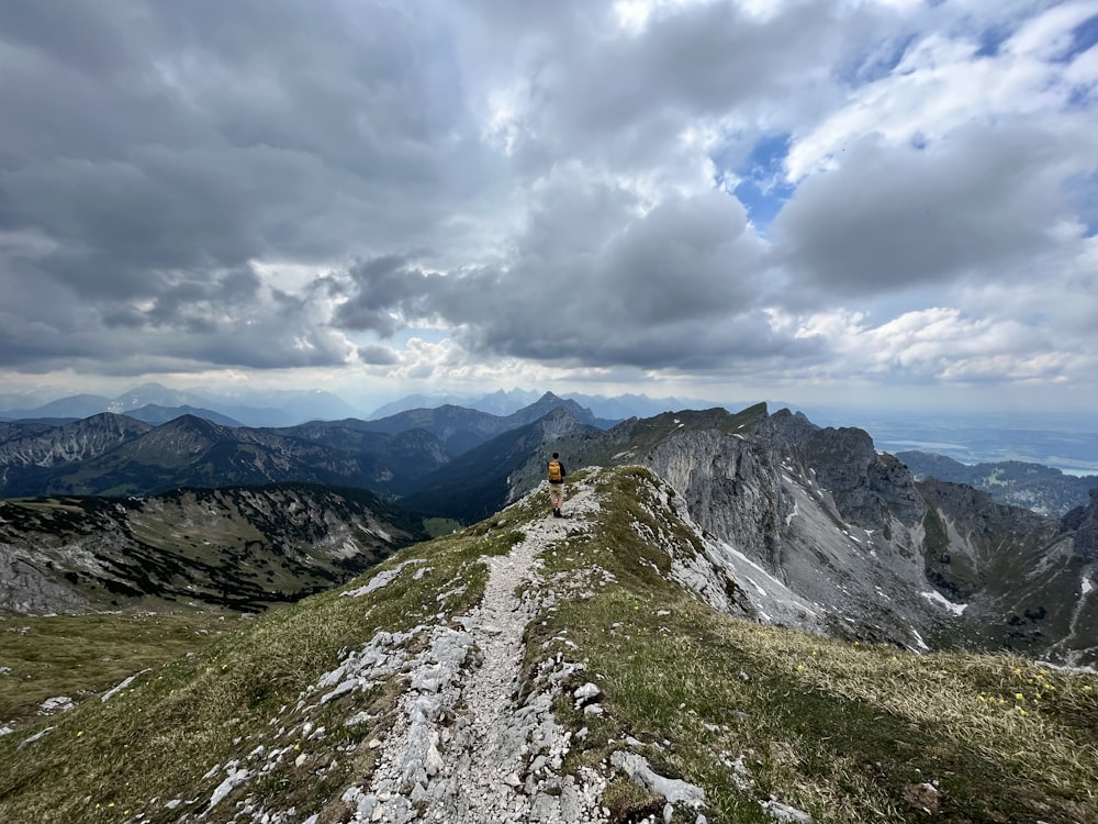 a person walking up a mountain trail on a cloudy day