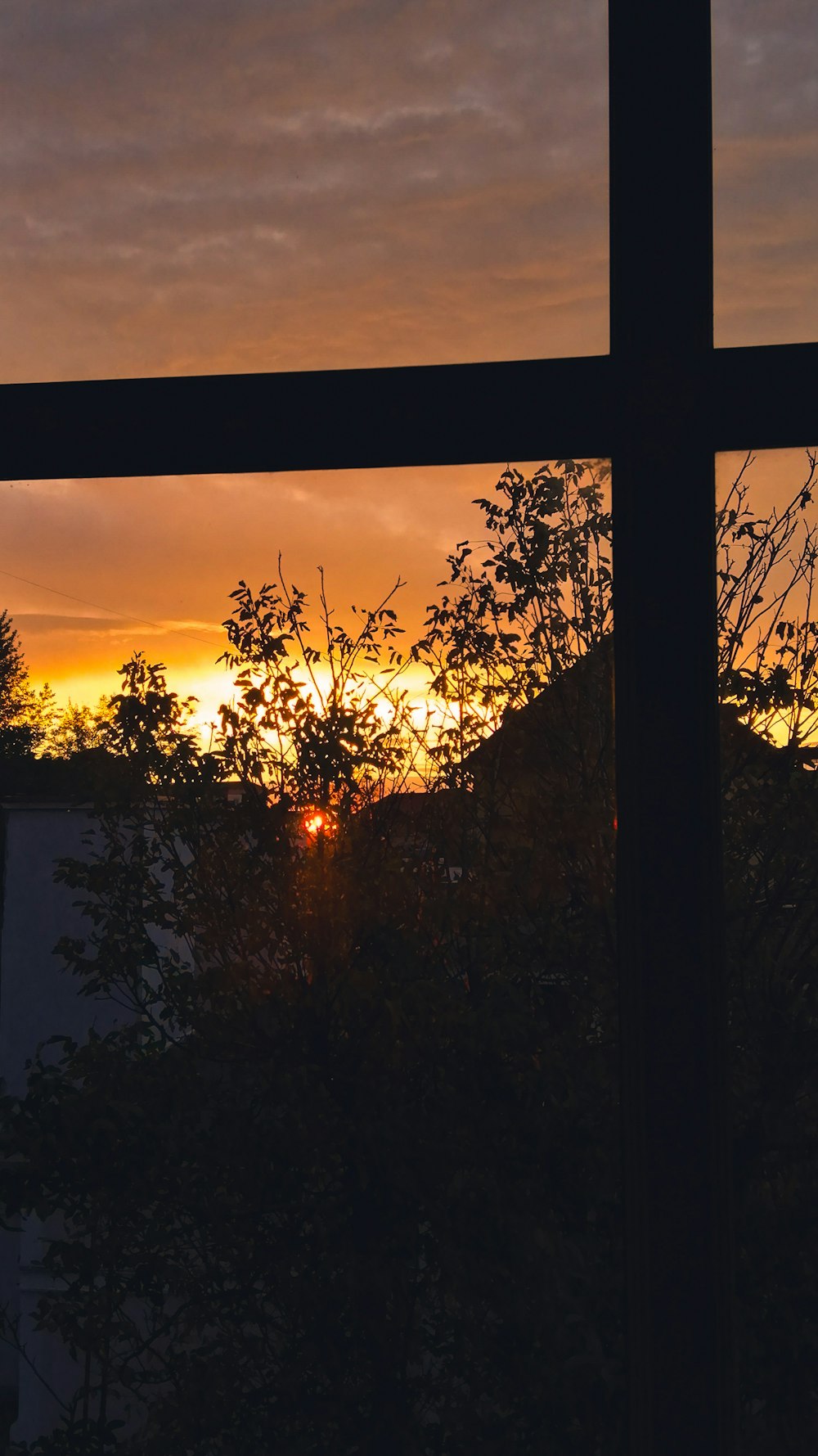 a sunset seen through a window with a cross in the foreground