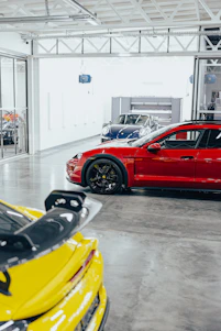 A modern luxury garage featuring dark gray epoxy flooring with gold accents and custom forged metal cabinets.