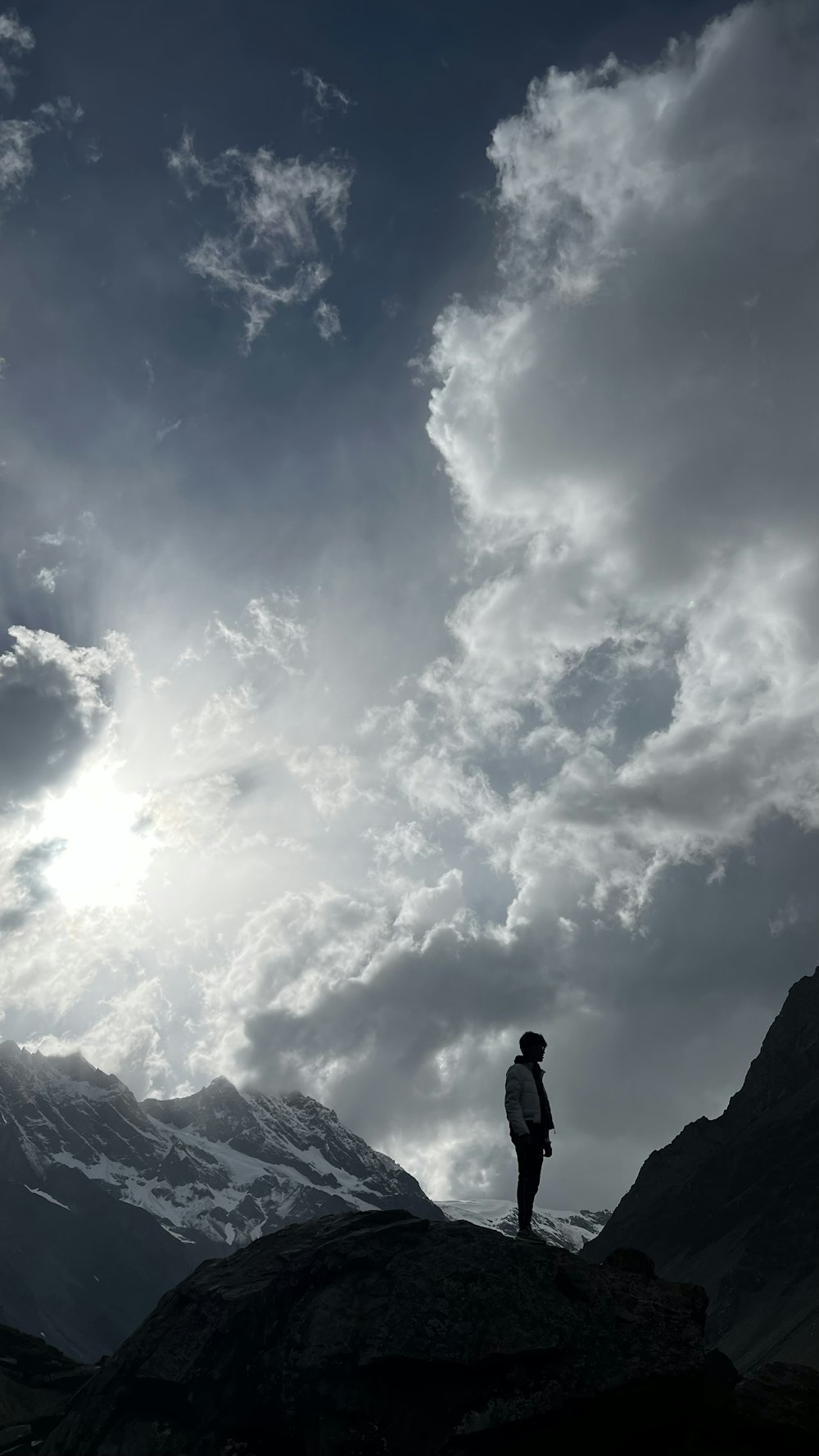 a person standing on top of a mountain under a cloudy sky